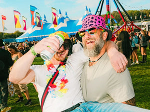 Two people at a festival with colourful flags and people in the background