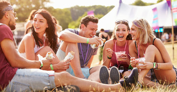 The Best Festival Food - friends sitting on grass eating and drinking at a music festival