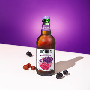 Brothers raspberry and blackberry cider bottle on a white surface with a purple background